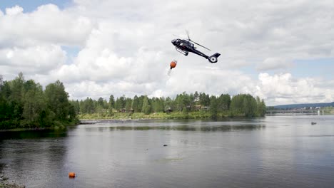 slow motion of the fire brigade rescue helicopter carries water in the tank in norway forest