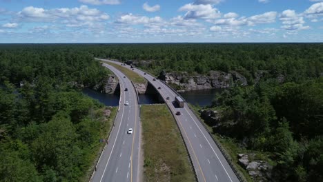 Low-traffic-flyover-of-curved-highway-bridge-through-rock-and-trees-near-Gravenhurst-Ontario