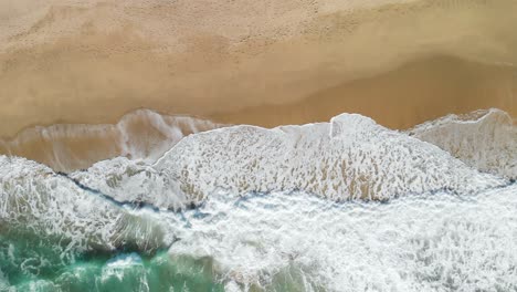 Top-down-still-aerial-shot-of-the-waves-crashing-on-the-California-Coast-near-Montara