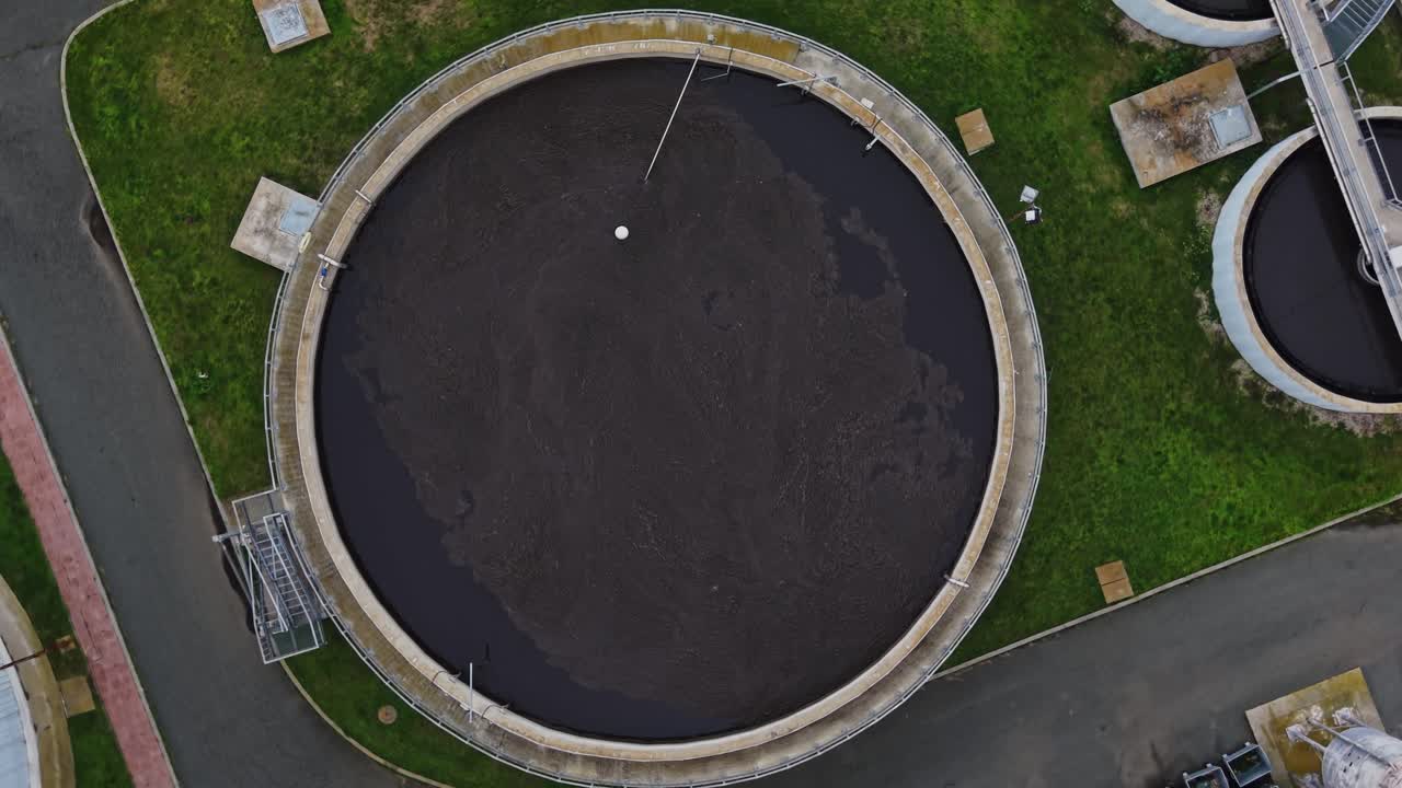 Water treatment facility with large tank and green surroundings during day