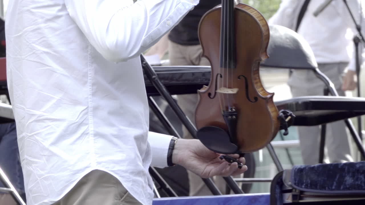 Man in white shirt putting a violin in it's case