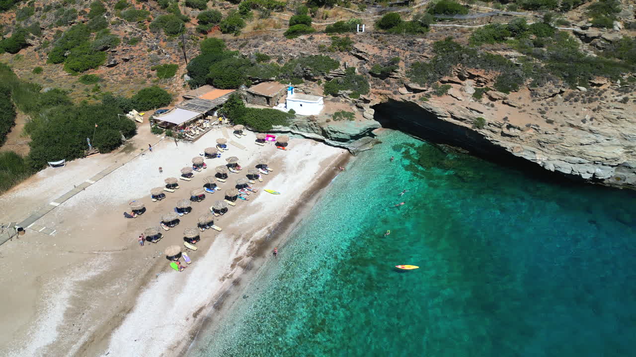 Aerial drone video from iconic sandy beach of Andros with sun beds and umbrellas, Cyclades, Greece