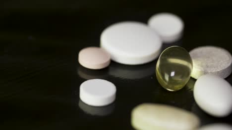 assorted pills and capsules on a dark surface