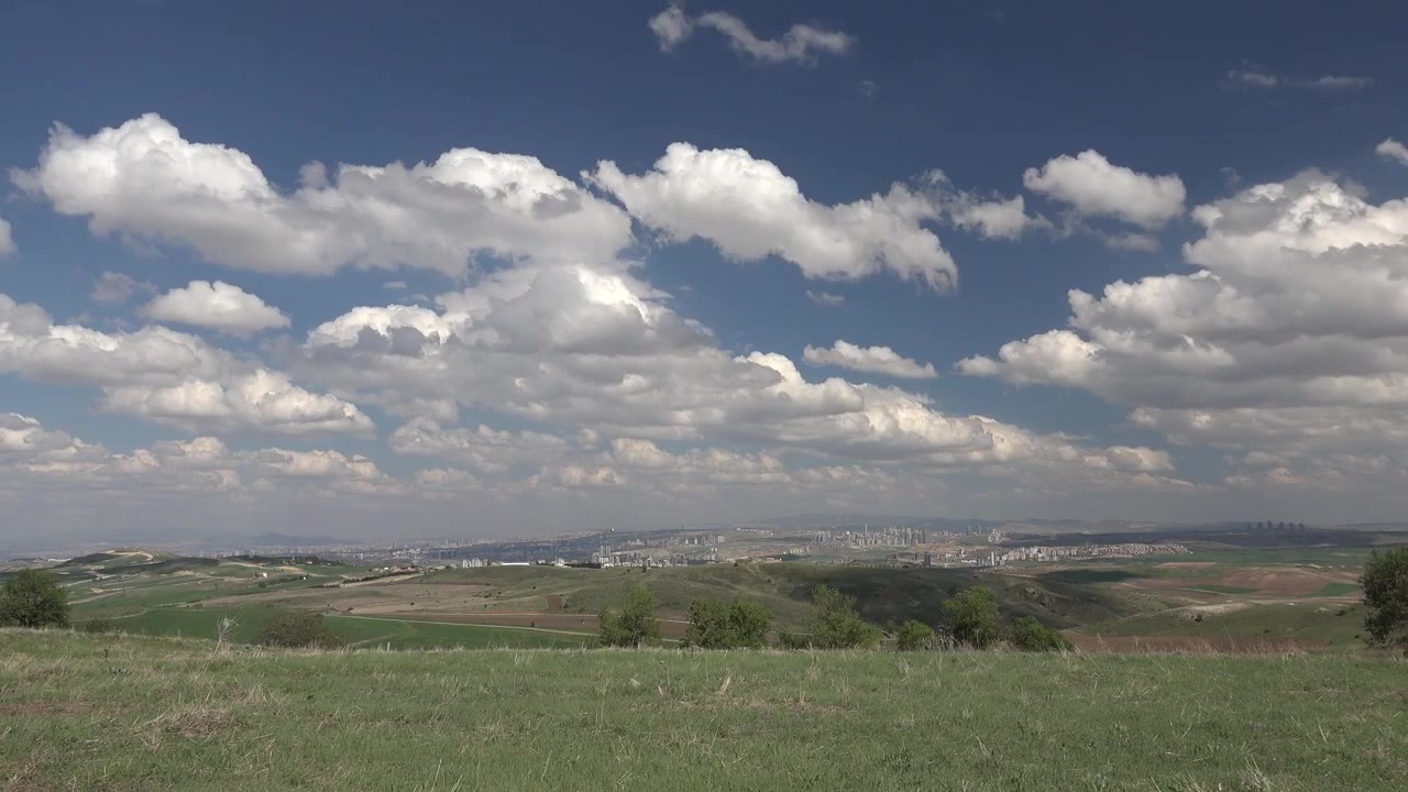 Panoramic View of Rolling Green Hills and Distant Cityscape