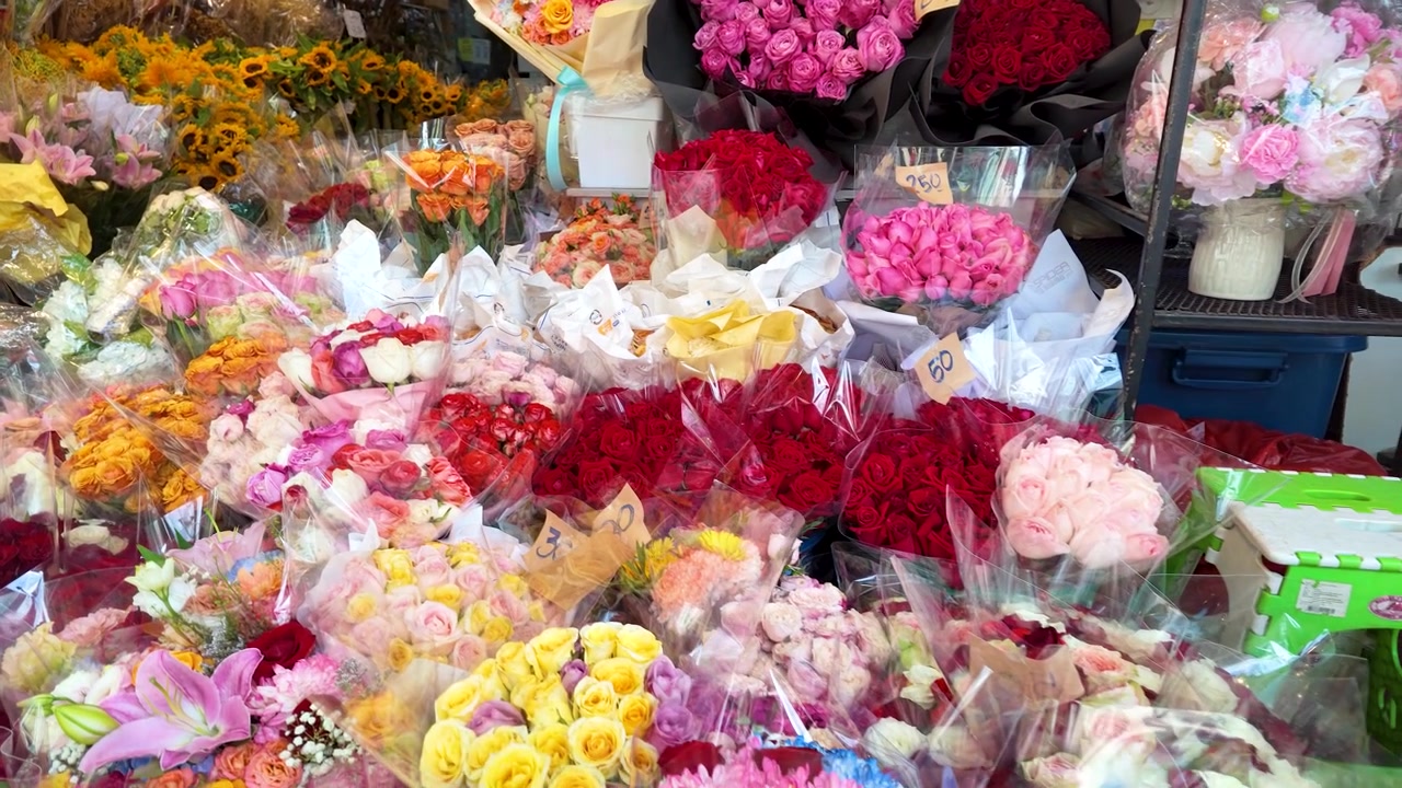 Statisk højvinkelbillede af diverse blomsterarrangementer og roser på et travlt udendørs marked