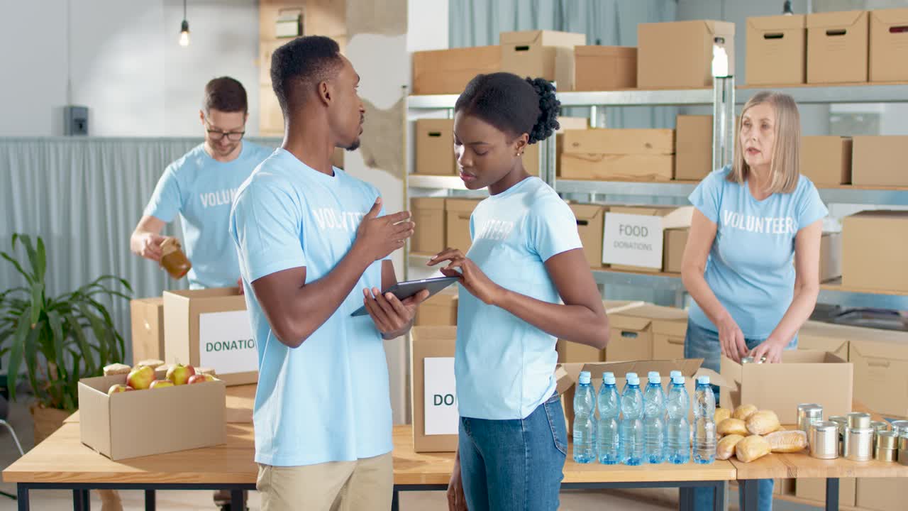 African American young male and female volunteers typing on tablet