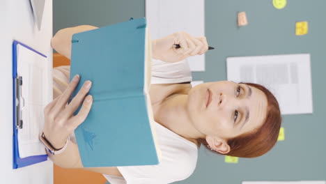 vertical video of woman with notebook thinks and takes notes.