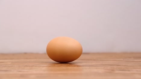 Farm-fresh-brown-egg-spinning-in-a-circle-on-a-wooden-cutting-board-in-slow-motion