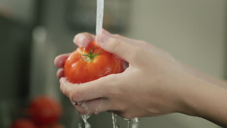 Mujer-Lavando-Tomate-Maduro-Bajo-Agua-Corriente-En-La-Cocina