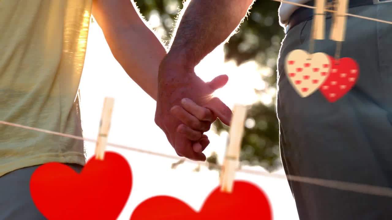 pareja de la mano en un día soleado con corazones para el día de san valentín