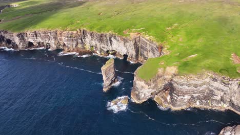 Aerial-View-of-Rock-Stack,-Steep-Cliff,-Green-Pastures-and-Blue-Sea-on-Coast-of-Scotland-UK-on-Sunny-Day-60fps