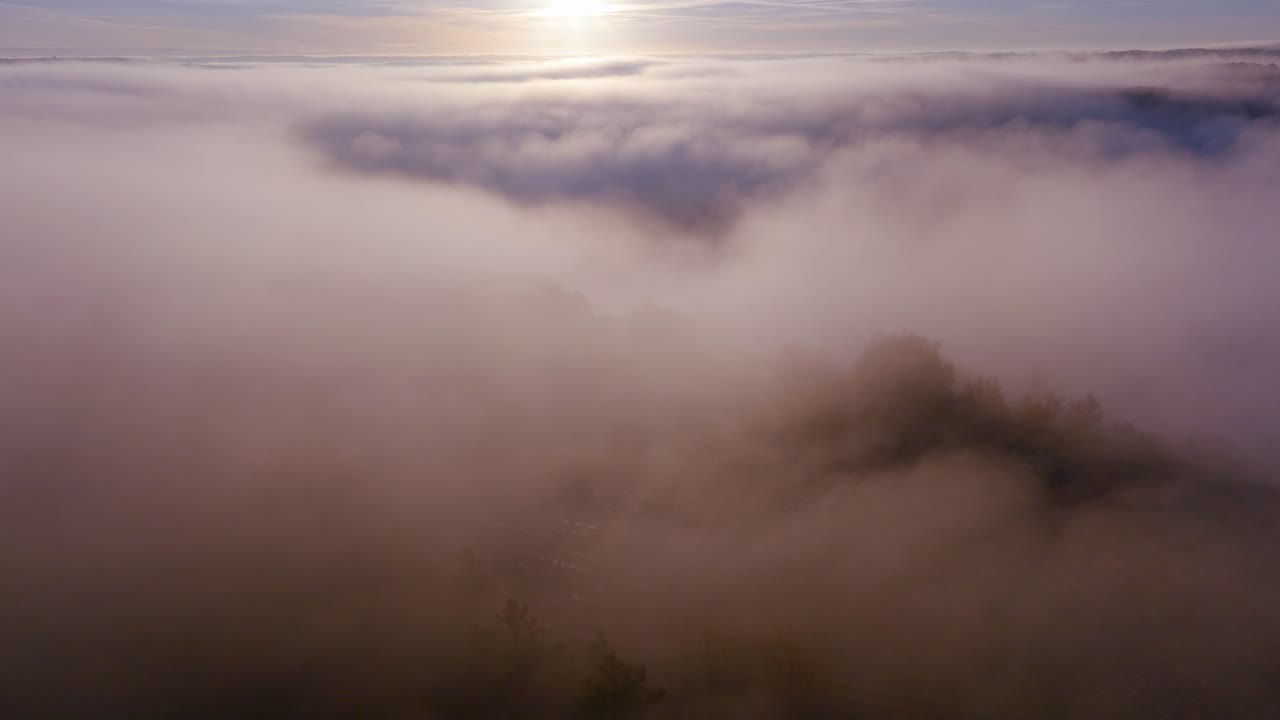 The first sun rays pierce a dense layer of clouds in a golden dawn glow.