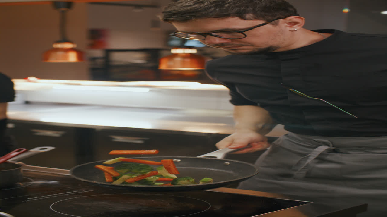Chef che salta le verdure in padella nella cucina di un ristorante