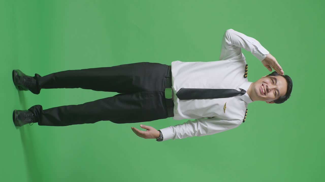 아시아 남성의 몸이 가득한 조종사는 존경스럽고, 녹색 스크린 배경 스튜디오에 서서 인사를합니다.