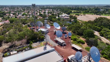 Satellite Communication Site With Dishes And Towers Near Suburban Housing On Sunny Day. aerial shot