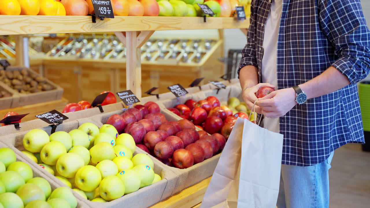 hombre comprando manzanas en una tienda de comestibles