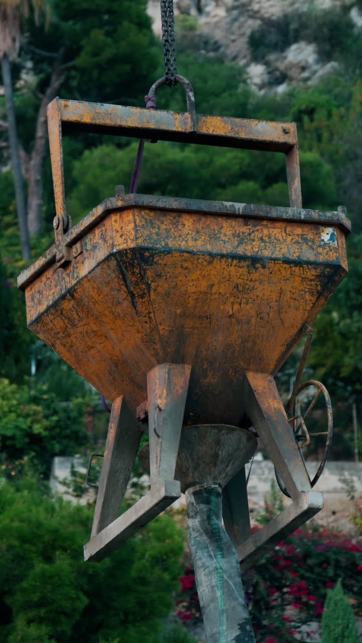 Primo piano di una vasca di cemento montata su una gru a torre per la costruzione. Verticale