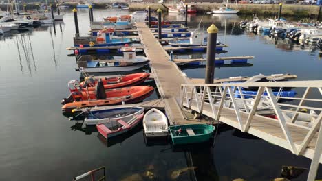 Many-fishing-and-leisure-boats-in-the-small-harbour-with-the-fish-market-building-in-the-background-in-a-bright-sunny-sunrise,-shot-revelation-upwards