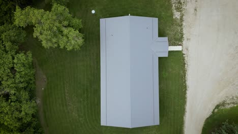 Cinematic-Aerial-Drone-Top-Down-Roof-Shot-Western-Canada-Pasture-Countryside-Agriculture-Demonstration-Cattle-Farm-House-Gain-Bins-and-Nature-Prairie-Field-Landscape-with-Highway-Riparian-Lake