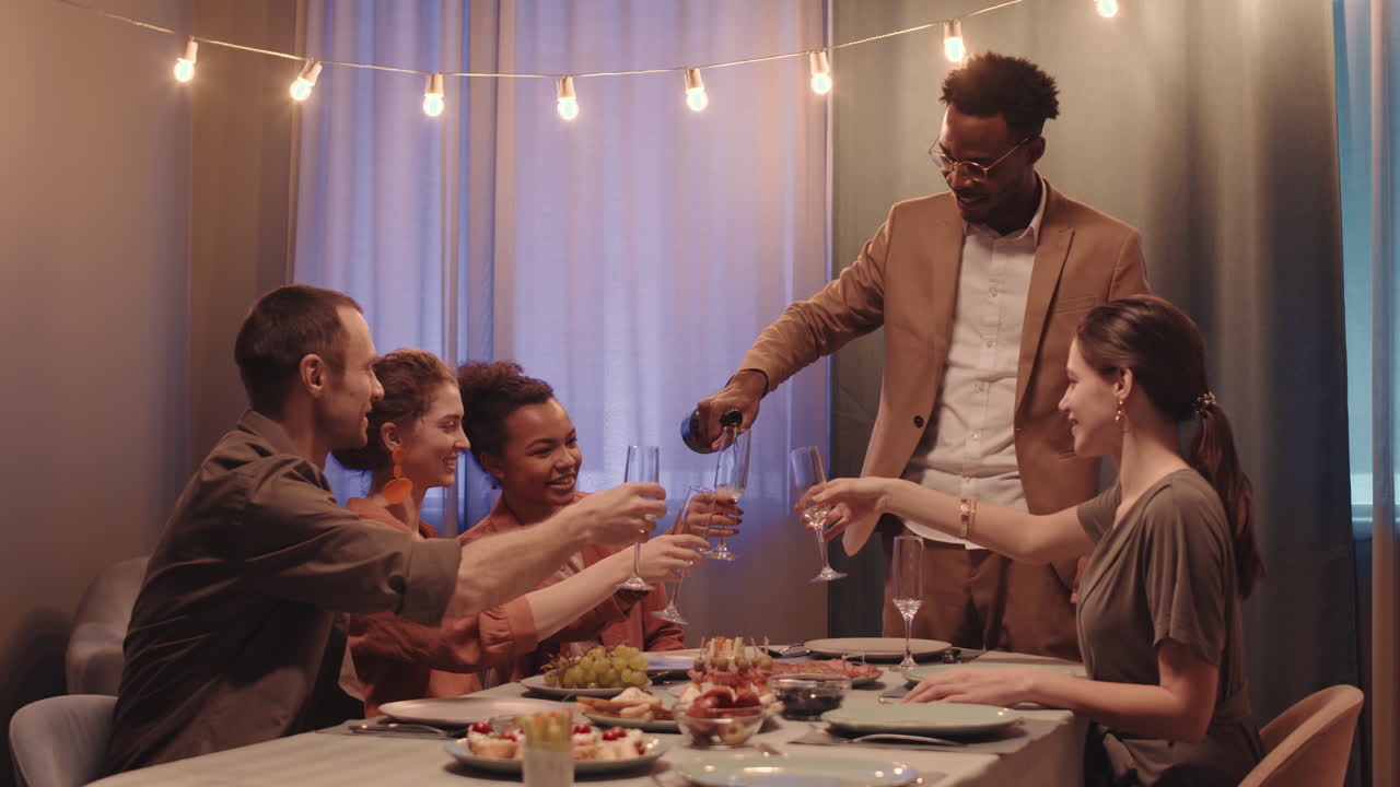 Afro American Man Opening Bottle of Champagne at Friends Dinner Party
