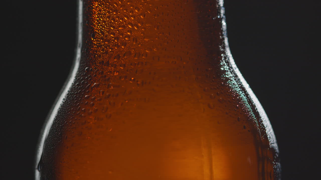 Close Up Of Condensation Droplets On Revolving Bottle Of Cold Beer Or Soft Drink