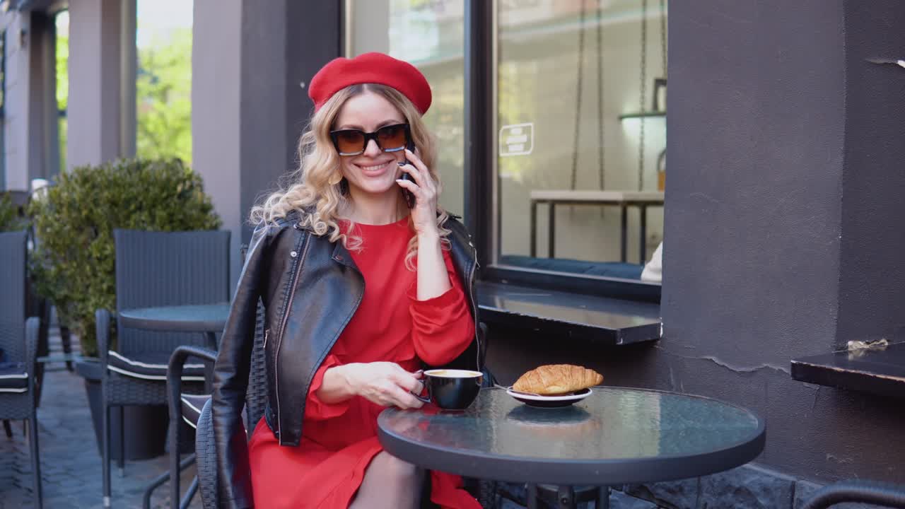 Coffee break with croissant. Modern urban young woman talking on cell phone on restaurant terrace