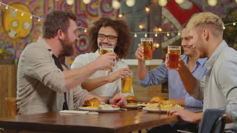 Amigos-Varones-Multiculturales-Sentados-A-La-Mesa-Comiendo-En-Un-Restaurante-Disfrutando-De-La-Noche-De-Chicas