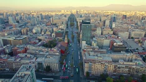 Alameda-street-leading-to-bicentenary-flag-and-san-francisco-church-at-sunset,-aerial-view-Santiago-Chile