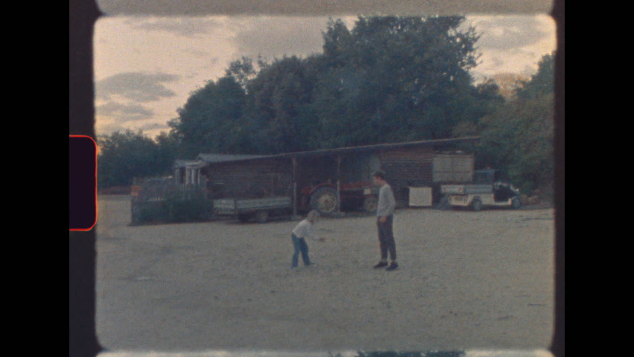 Brother and sister playing catch in rustic farmyard - vintage footage