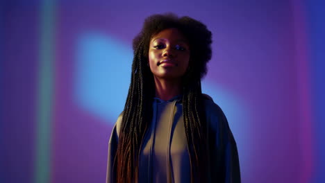 young woman with braided hair in hoodie against neon background