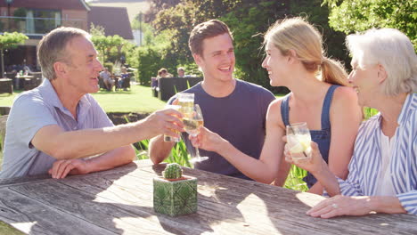 parents with adult offspring enjoying outdoor summer drink at pub