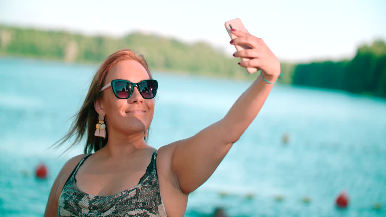 Donne caucasiche felici e allegre che si scattano un selfie in riva a un lago.