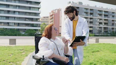 doctor consulting with patient in wheelchair outdoors