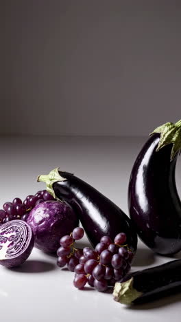 a vibrant display of purple vegetables and fruits, including eggplants, red cabbage, and grapes