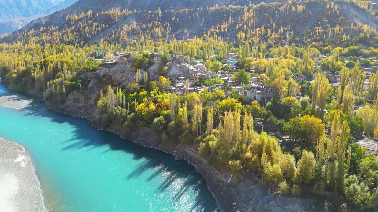drone disparado sobre skardu en pakistán río turquesa y árboles verdes con montañas en el fondo