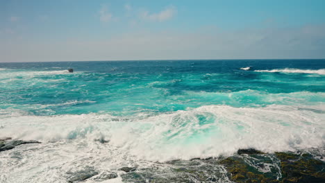 slow motion shot of rough ocean waves crushing against the volcanic rocky coastline