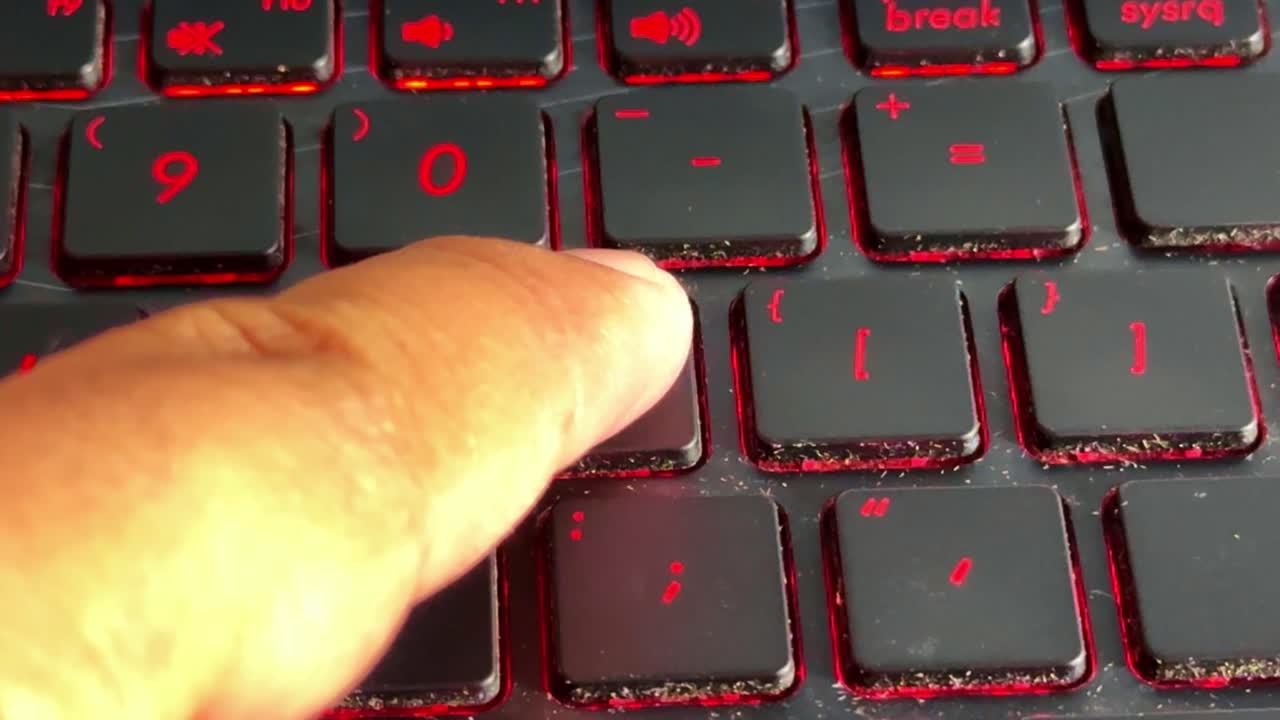Close-up typing action on a laptop keyboard in "p" button with red backlight, showcasing modern computing and office tasks