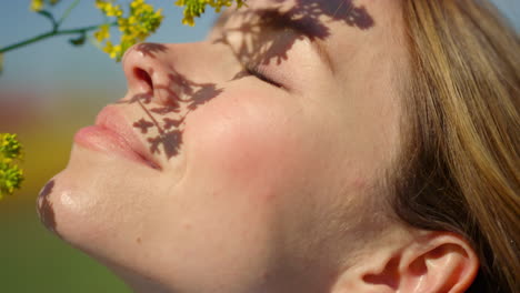 close up beautiful woman plying with blooming wild flower in daylight outdoors.