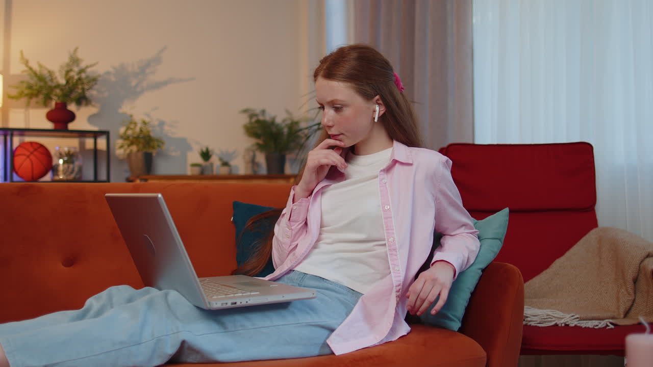 Teen child girl kid freelancer working on laptop, sends messages, makes online purchases at home