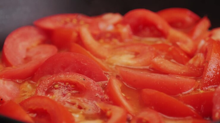 Cooking fresh peeled sliced tomato Juice sauce in pan, peeled tomatoes boiling in their own juice, making tomatoes pasta sauce .Top view close up, Italian traditional cuisine food.