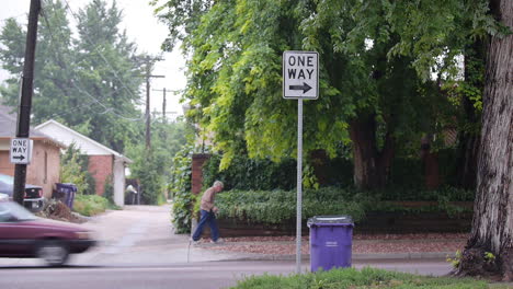 senior citizen jogs down suburban street labeled one way as cars drive way