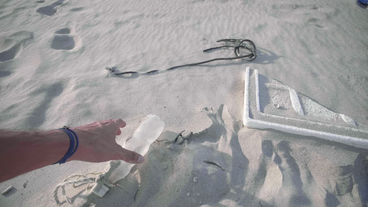 Cleaning up beach of plastics, bottles, ropes and other domestic trash. A first person view. 4K.