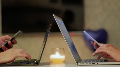 las manos de la pareja de estudiantes trabajando en teléfonos inteligentes y portátiles de cerca