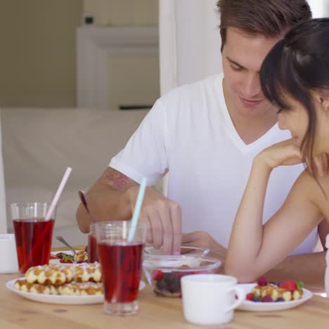 man feeding his wife fruit at breakfast