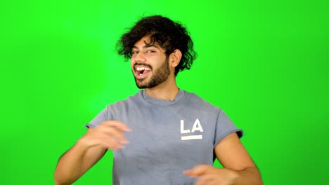 Indian-guy-showing-up-and-saying-hello-to-the-camera-with-waving-hand-with-green-background---green-screen