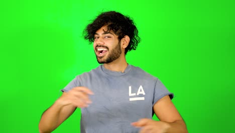 indian guy showing up and saying hello to the camera with waving hand with green background - green screen