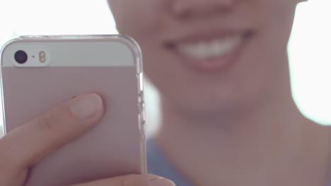una joven asiática sonríe al usar un smartphone