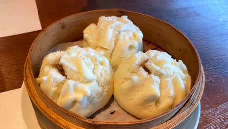 bollos de bao calientes con cerdo especiado en una cesta de bambú, apertura de la mano del hombre, bollos al vapor en un restaurante, cocina asiática tradicional, 4k