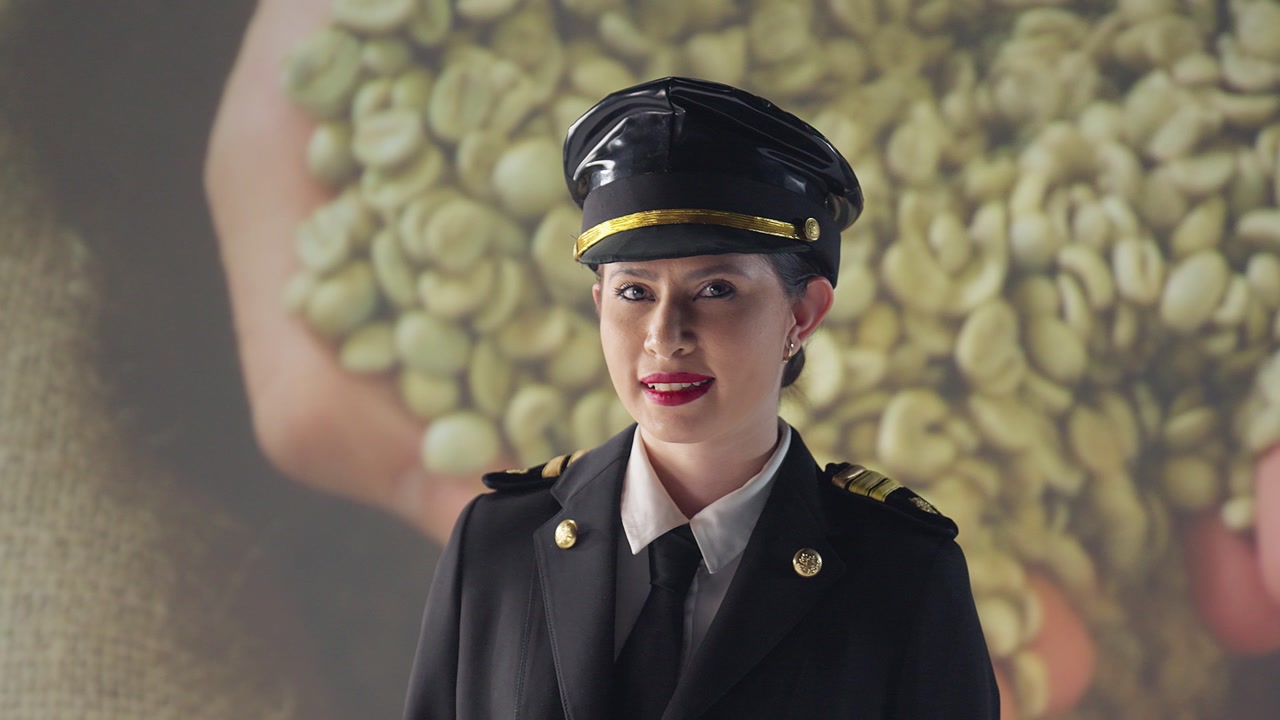 Female airplane pilot in uniform smiles and poses for the camera, while background images of healthcare professionals circulate, conveying peace, love, and teamwork along a cargo line.