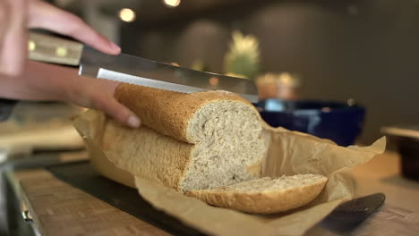 close up of female hands slicing loaf of bread